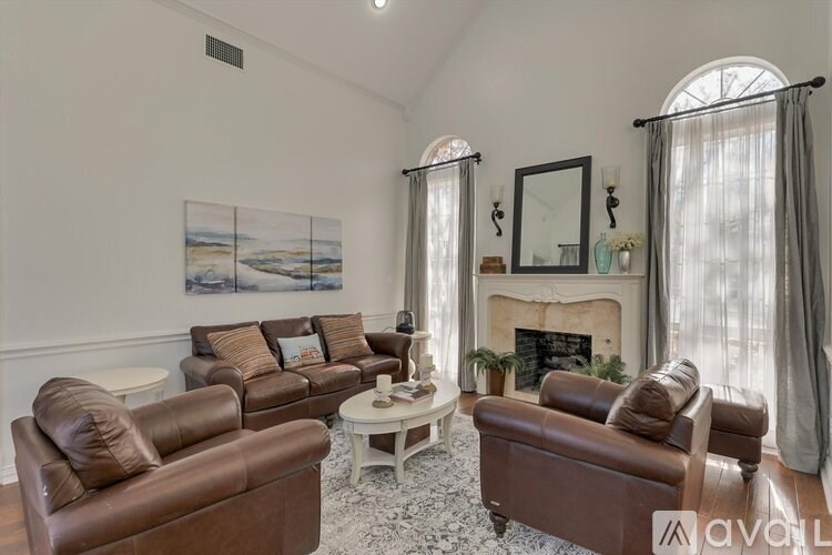 A living room with brown leather furniture and a fireplace.