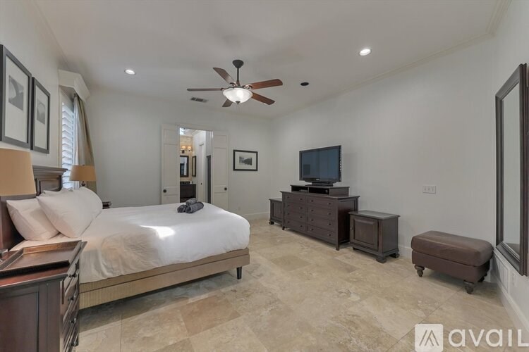 A bedroom with a large bed, a dresser, and a television.