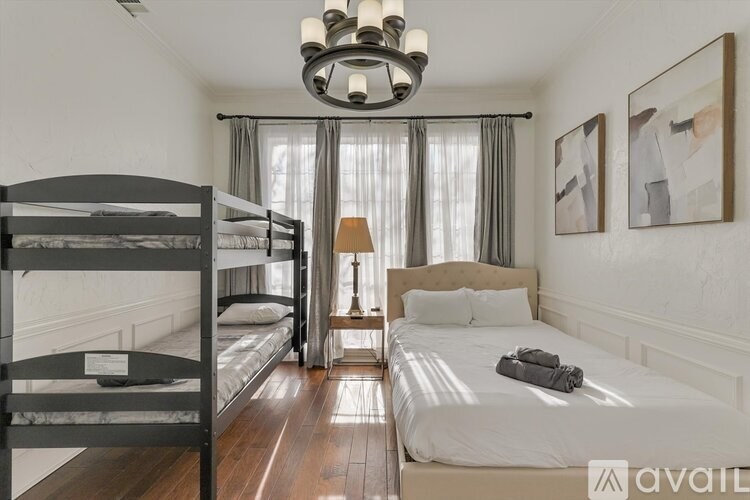 A bedroom with a bunk bed and a single bed with a lamp on the side table.