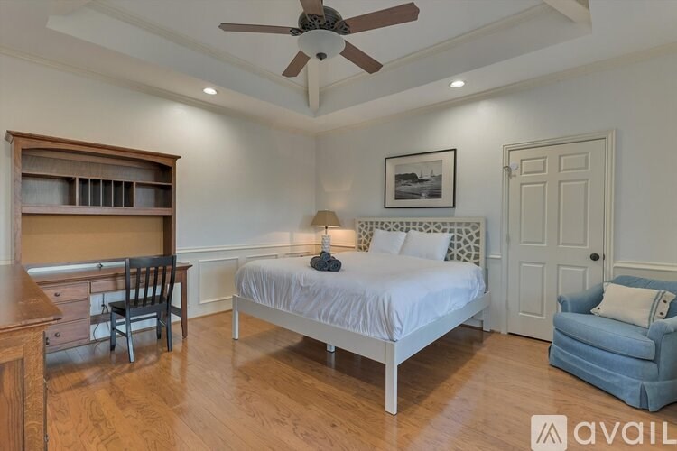 A bedroom with a bed, chair, and a ceiling fan.