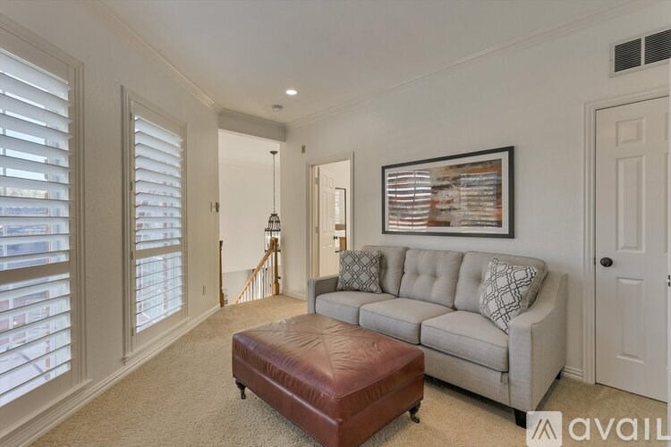 A living room with a grey couch and a brown ottoman.
