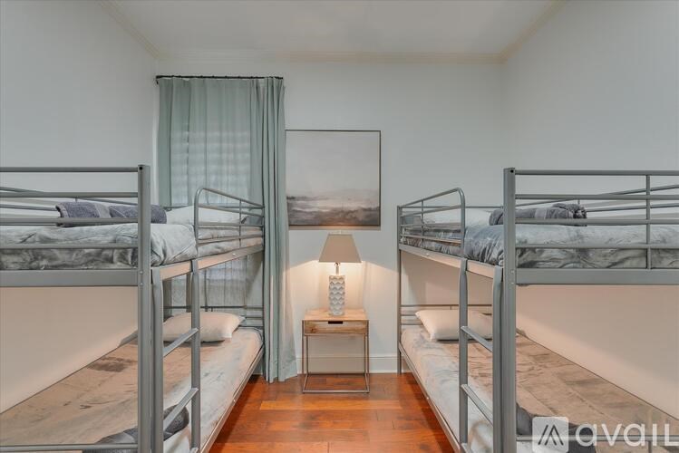 A room with bunk beds and a table with a lamp on it.