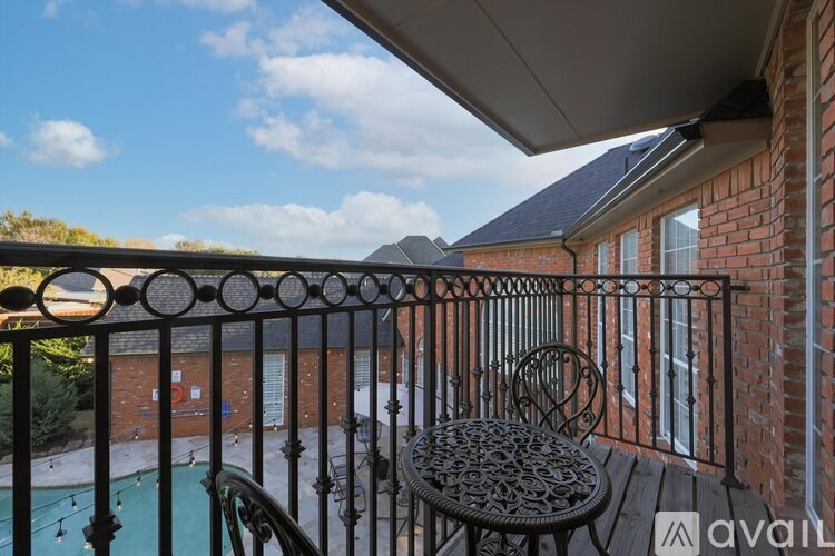 A balcony with a table and chairs overlooking a pool.