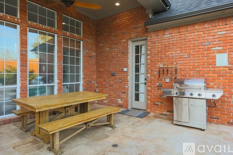 A red brick house with a wooden table and bench outside.