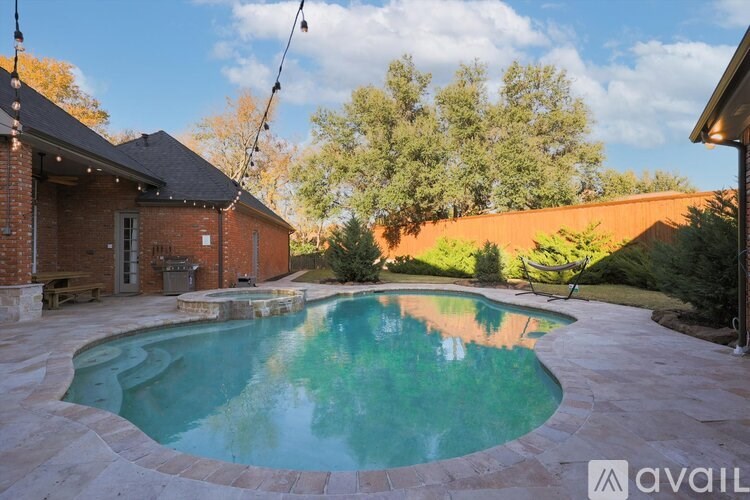 A swimming pool in a backyard with a house and trees in the background.