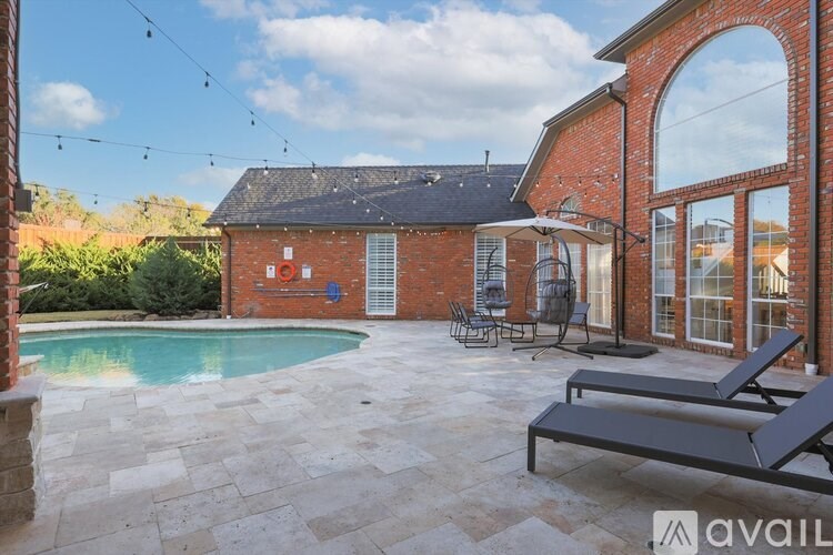 A backyard with a pool and patio furniture.