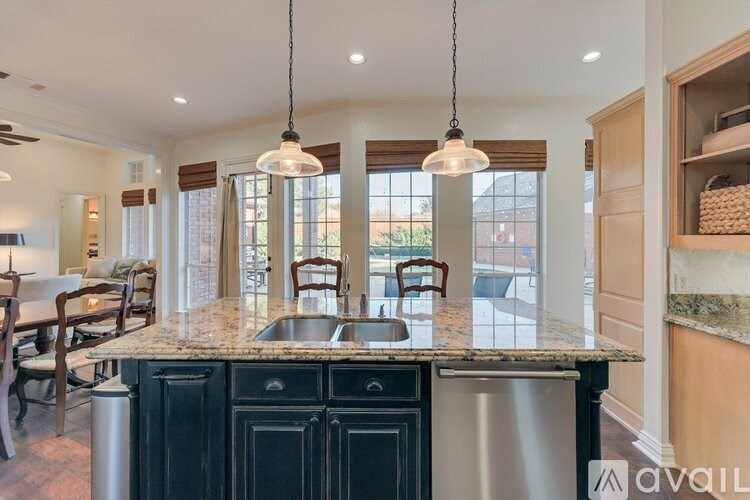 A kitchen with a granite countertop and a sink under a window.