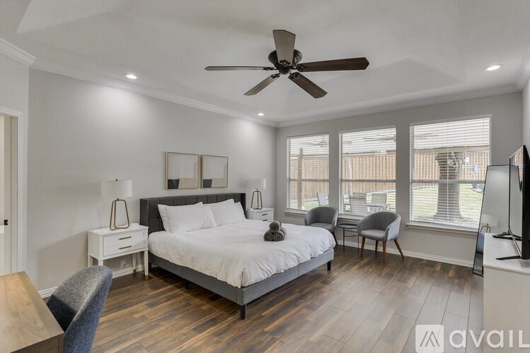 A bedroom with a large bed, a ceiling fan, and a television.