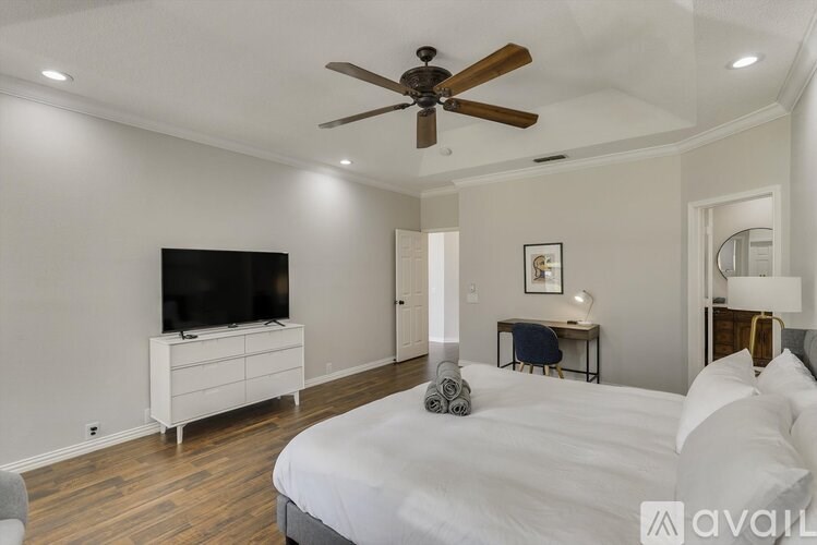 A bedroom with a large bed, a television, and a desk.