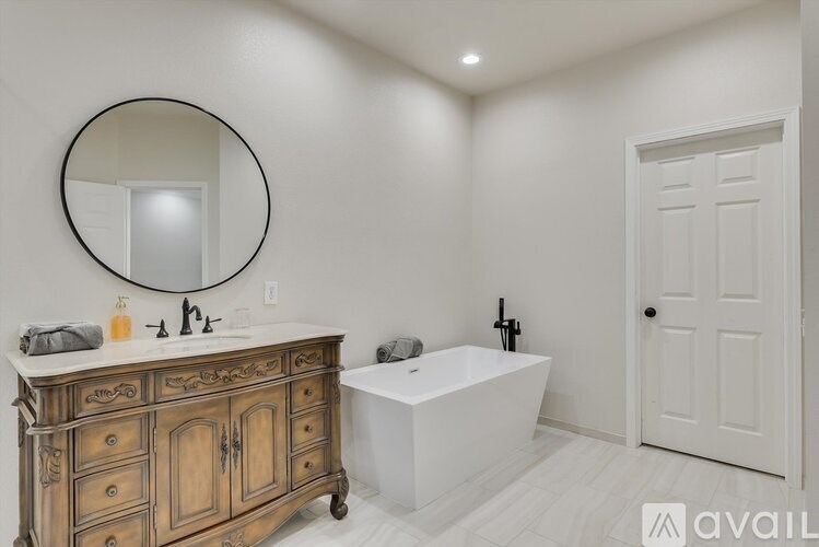 A bathroom with a wooden vanity and a white bathtub.