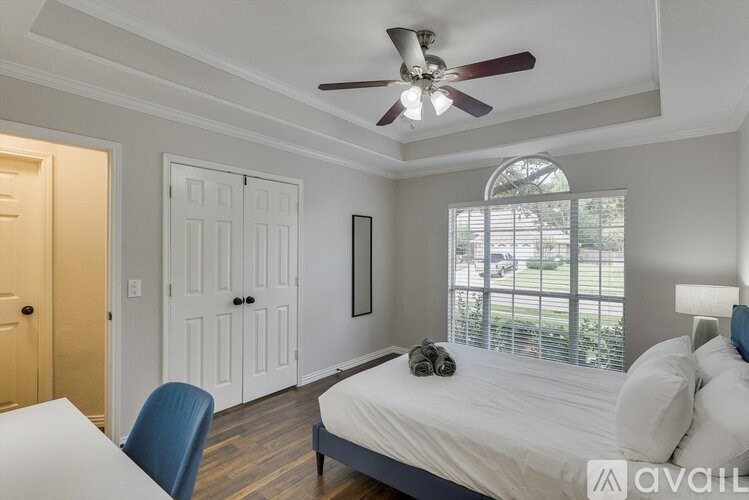 A bedroom with a bed, a chair, and a ceiling fan.
