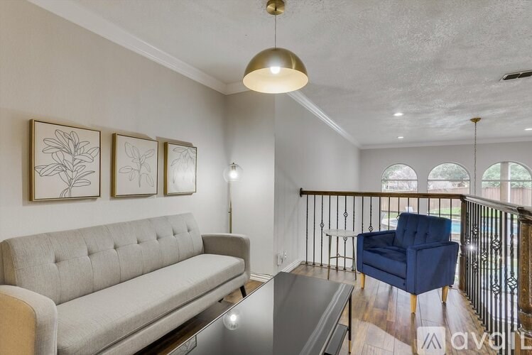 A living room with a grey couch, a blue armchair, and a glass table.
