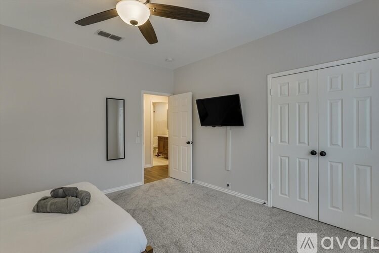 A bedroom with a bed, a ceiling fan, and a door leading to another room.