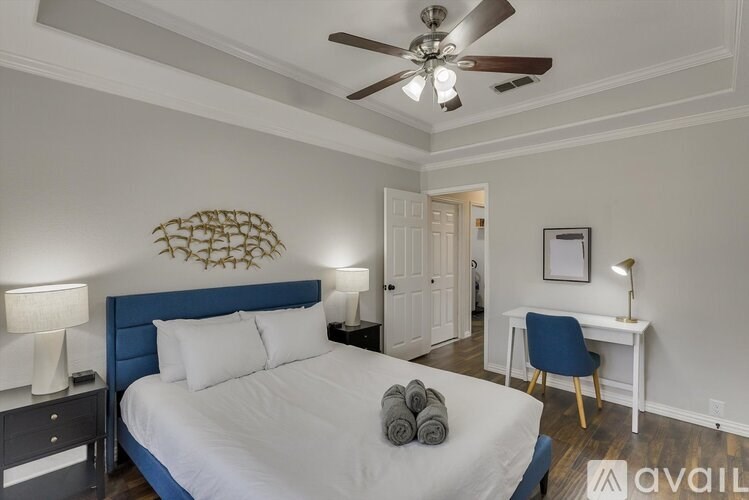 A bedroom with a bed, desk, and ceiling fan.