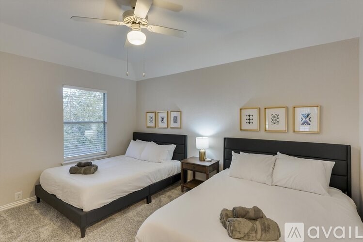 A bedroom with two beds, a ceiling fan, and wall art.