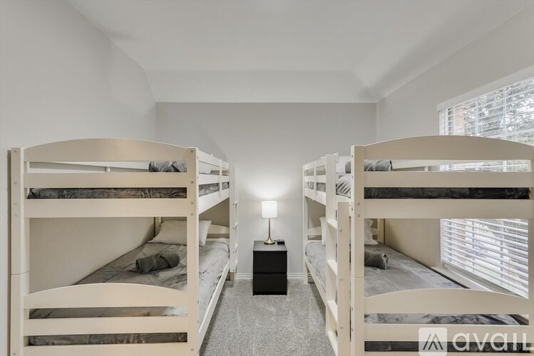 A room with white walls and a carpeted floor has two bunk beds.