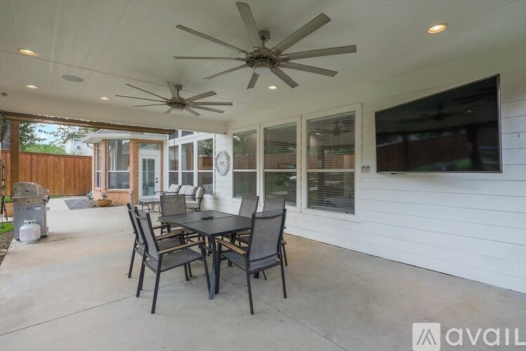 A patio with a table and chairs and a ceiling fan.