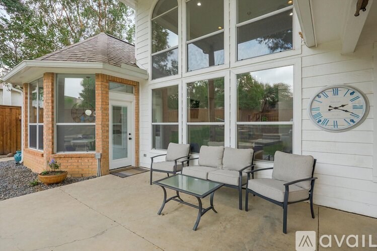 A patio with a table and chairs and a clock on the wall.