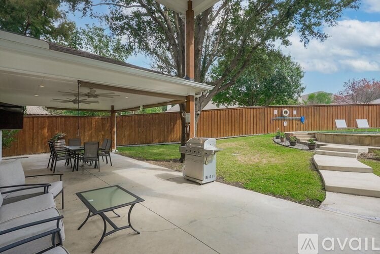 A patio with a glass table and chairs under a roof.