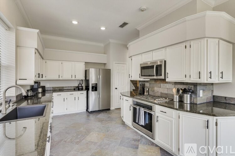 A kitchen with white cabinets and a black countertop.
