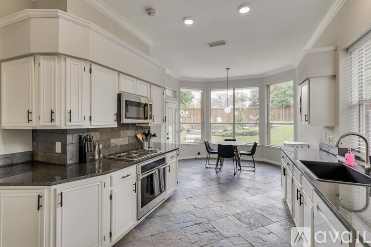 A kitchen with white cabinets and black countertops.