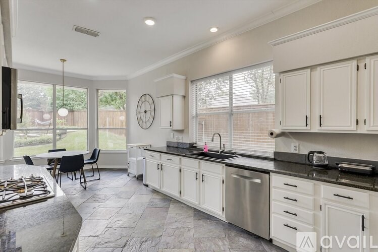 A kitchen with white cabinets and a black countertop.