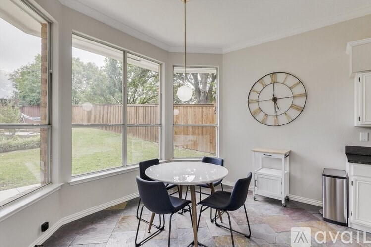 A dining room with a table and chairs and a clock on the wall.