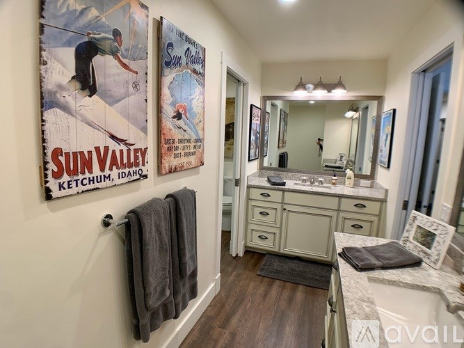 A bathroom with a poster of a snowboarder and a Sun Valley Ketchum Idaho poster on the wall.