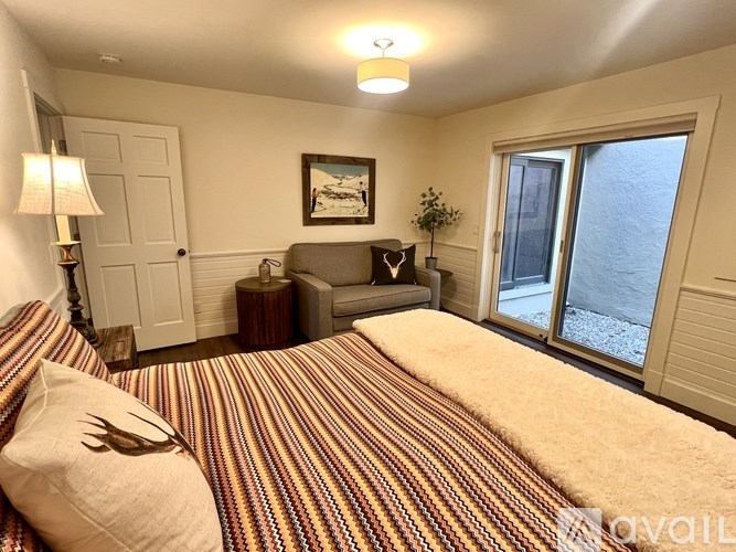 A bedroom with a striped bedspread and a painting on the wall.