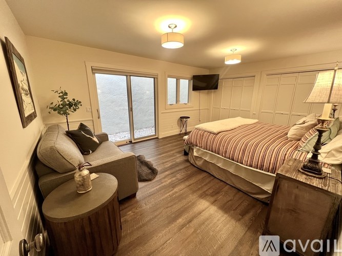 A bedroom with a large bed and a couch with a pillow and a plant on it.