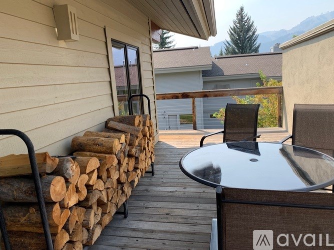 A patio with a table and chairs and a stack of logs.
