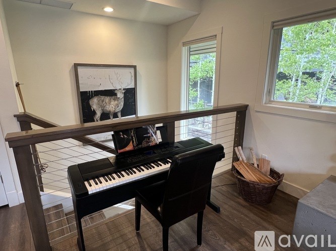A black piano sits in a room with a framed picture of a deer on the wall.