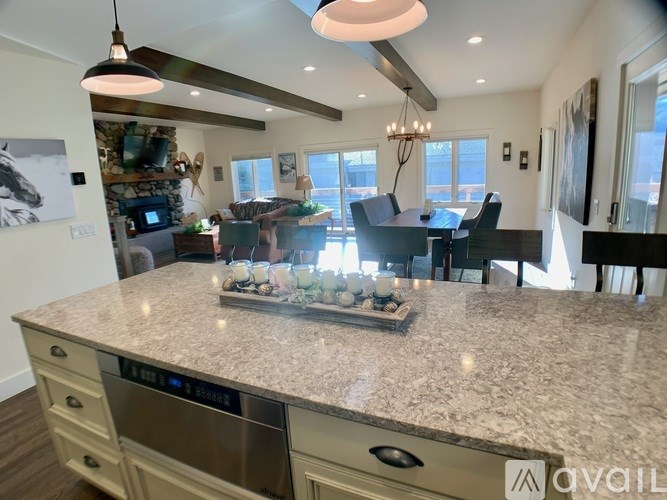 A kitchen with a marble countertop and a dining area with a table and chairs.