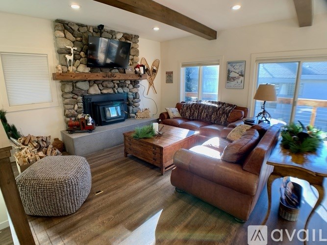 A living room with a stone fireplace and a flat screen TV mounted above it.