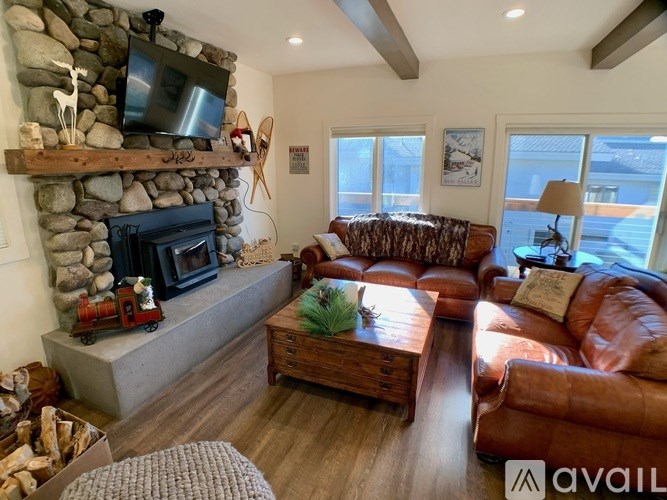 A living room with a stone fireplace and a brown leather couch.