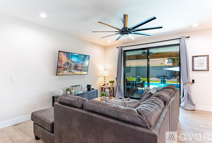 A living room with a brown couch and a ceiling fan.