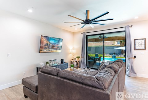 A living room with a brown couch and a ceiling fan.