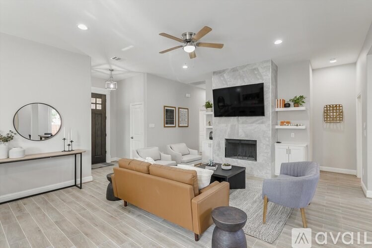 A living room with a fireplace and a television mounted above it.