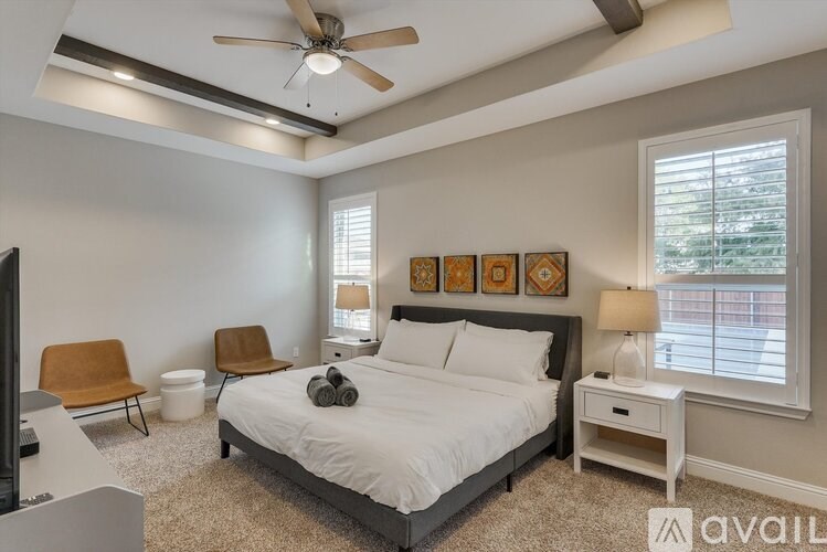 A bedroom with a bed, chair, and ceiling fan.