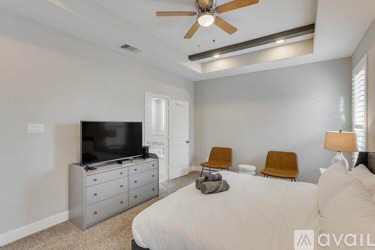 A bedroom with a bed, a television, and a ceiling fan.