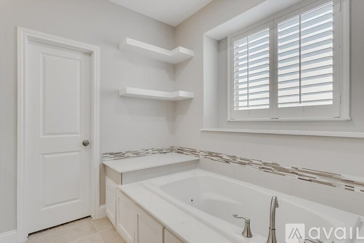 A white bathroom with a window and a sink.