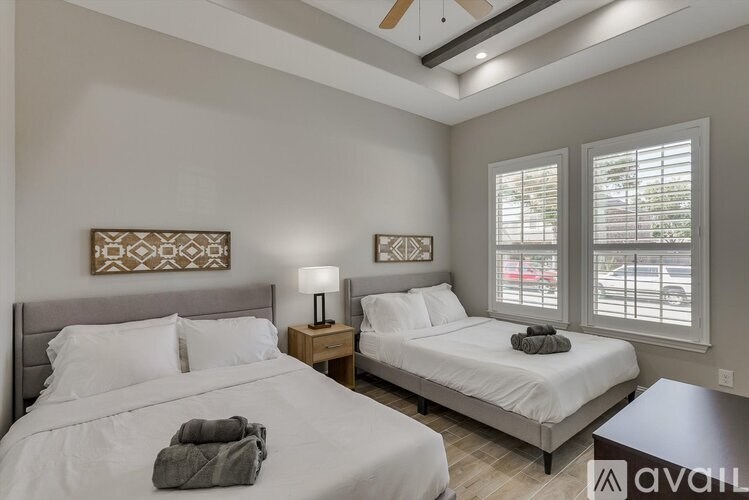 A bedroom with two beds, one with a grey blanket on it.