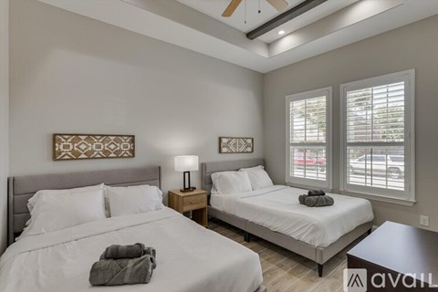 A bedroom with two beds, one with a grey blanket on it.