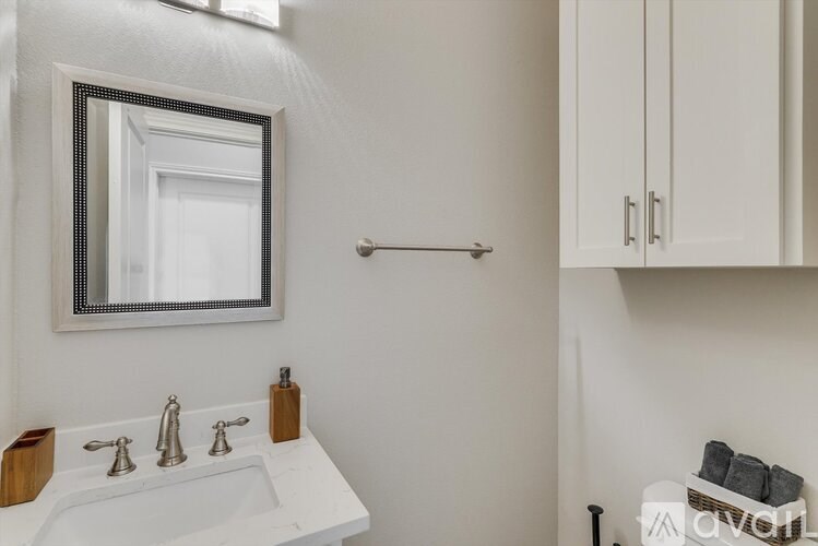 A white sink with a silver faucet and a mirror above it.