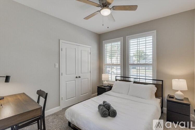 A bedroom with a bed, nightstand, and a table with a chair.