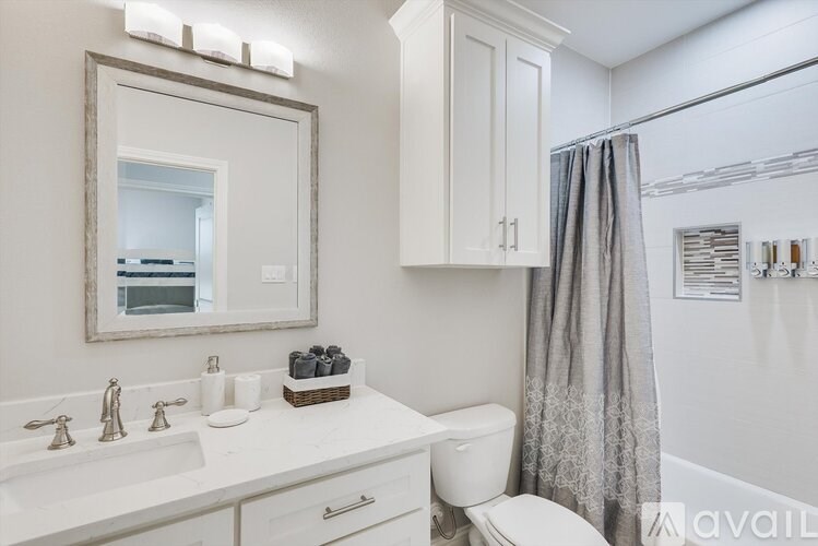 A bathroom with a white toilet, sink, and a mirror.