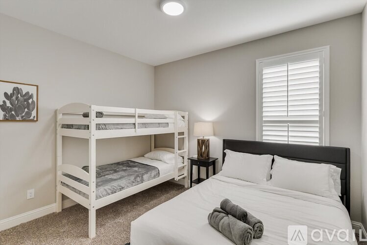 A bedroom with a white bed and bunk beds.