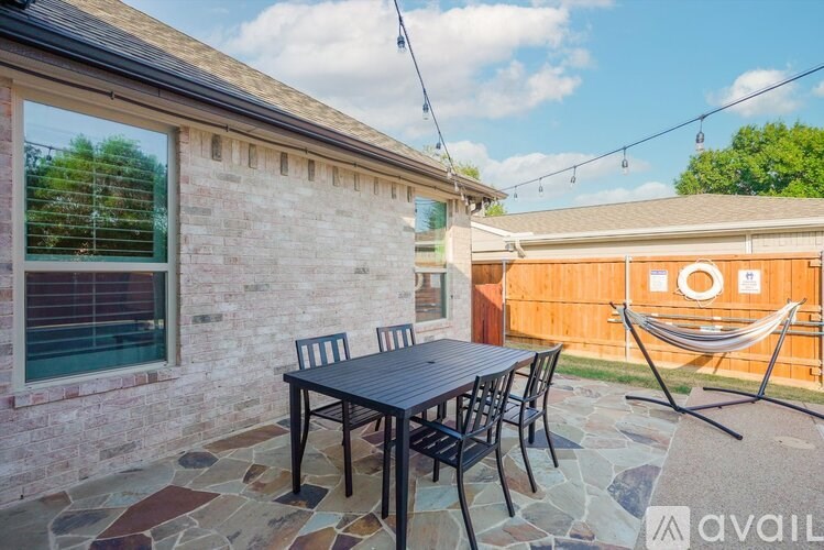 A patio with a table and chairs and a hammock.
