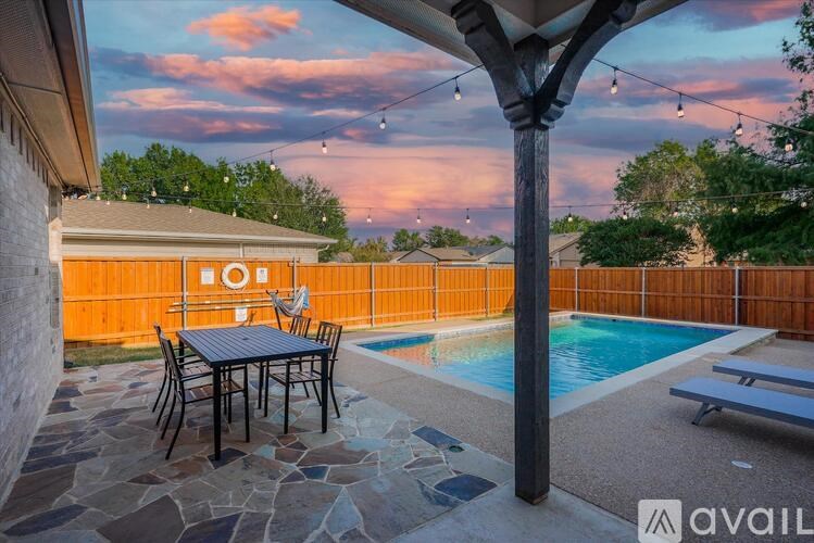 A patio with a table and chairs is set up next to a pool.