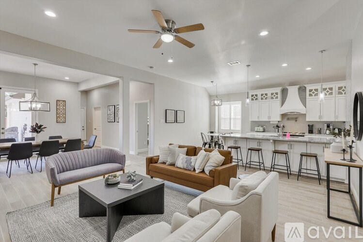 A modern living room with a grey sofa, a black coffee table, and a bar area in the background.